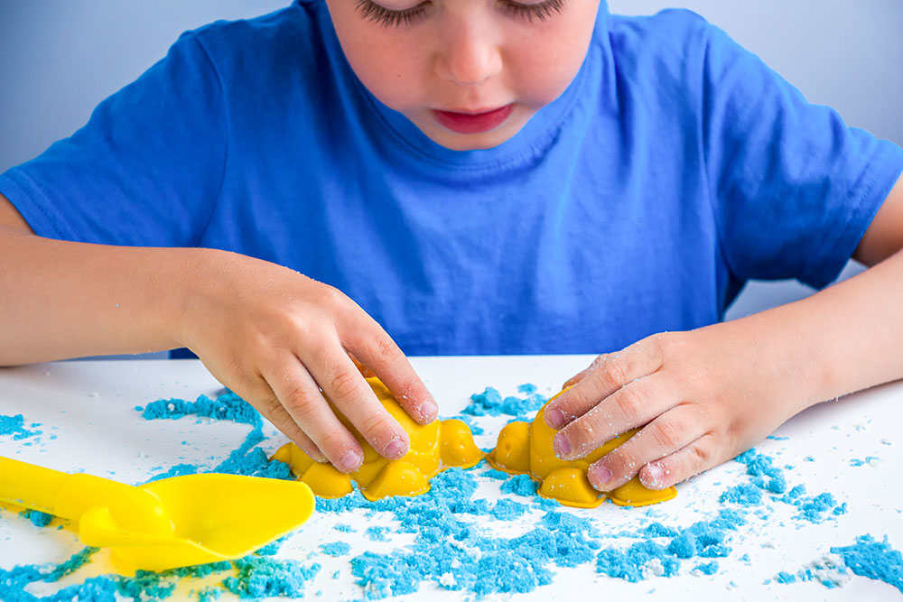 "Boy Playing with Kinetic Sand: Hands-On Learning and Fine Motor Skills Enhancement"